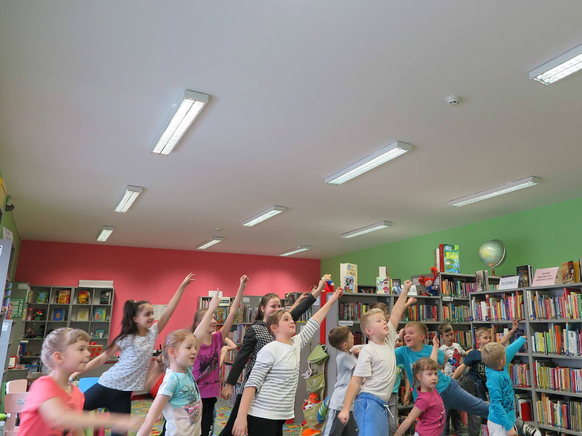 Wnętrze biblioteki. Dzieci wykonują układ taneczny zumby. 