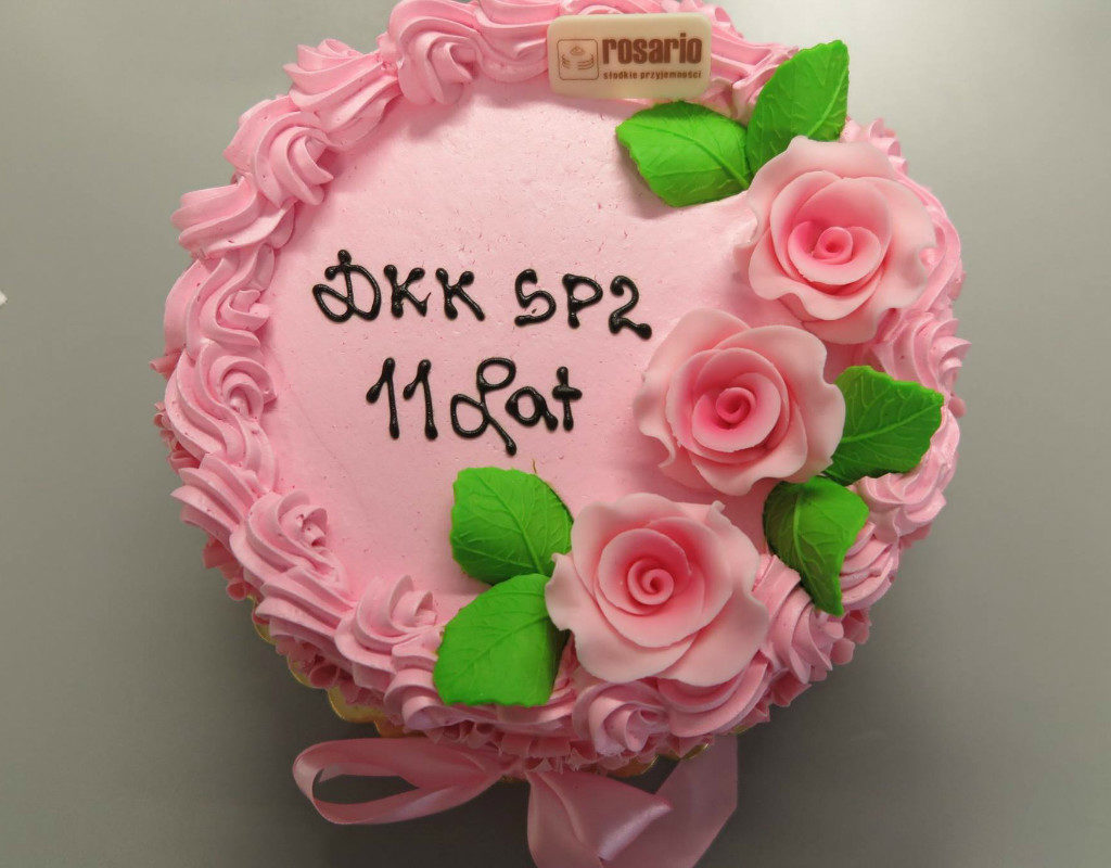 Różowy tort z różyczkami i napisem DKK SP 2  11 lat. 