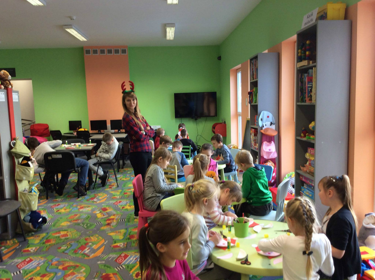 Wnętrze biblioteki. Przy stolikach siedzą dzieci ze SP NR 3 biorą udział w zajęciach edukacyjnych.