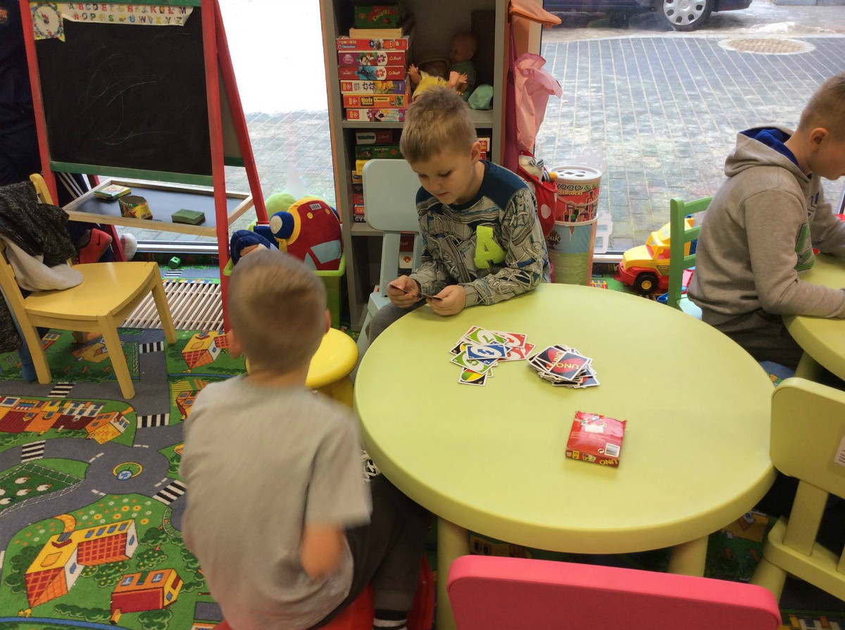 Przy stoliku siedzi dwóch chłopców i gra w karty. 