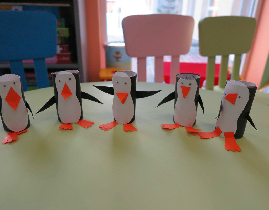 Na stoliku stoi 5 pingwinów zrobionych  z rolek papieru przez dzieci.