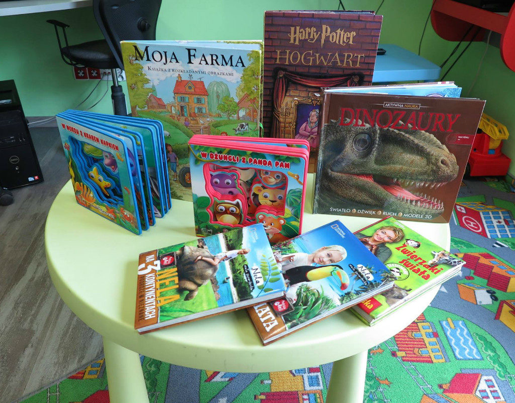 Na zielonym stoliku znajdują się książki dla dzieci m.in. Harry Potter pt.''Hogwart'', Aktywna Nauka ''Dinozaury'', Moja Farma, Nela na trzech kontynentach. 