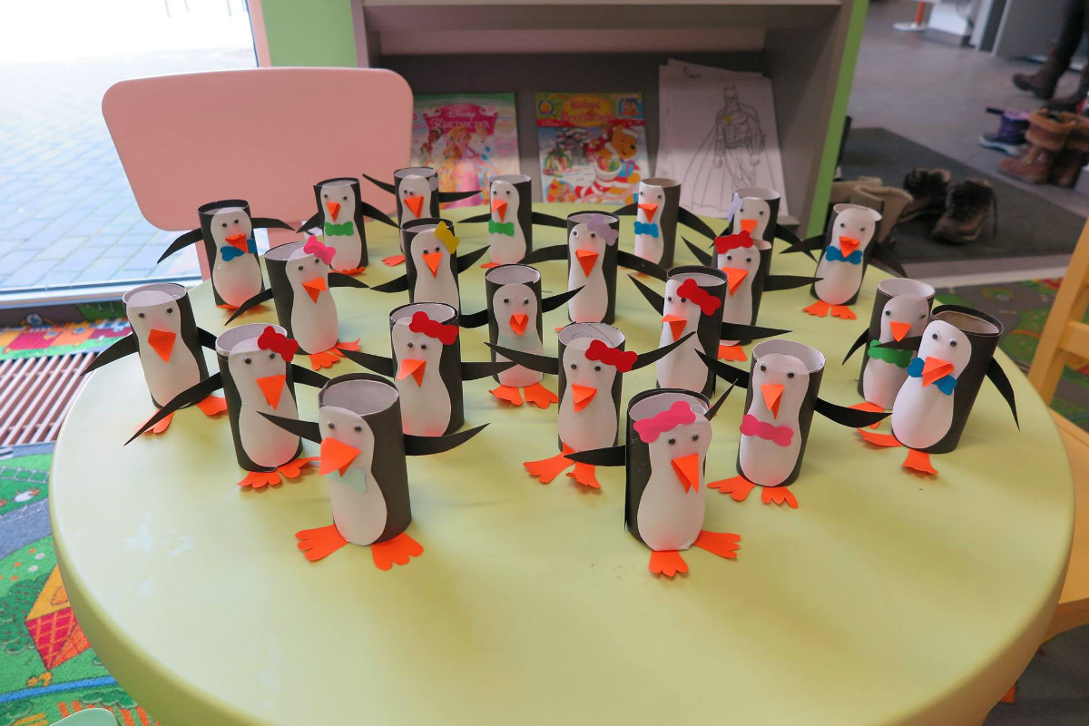 Na stoliku stoją pingwiny wykonane z rolki papieru przez dzieci. 