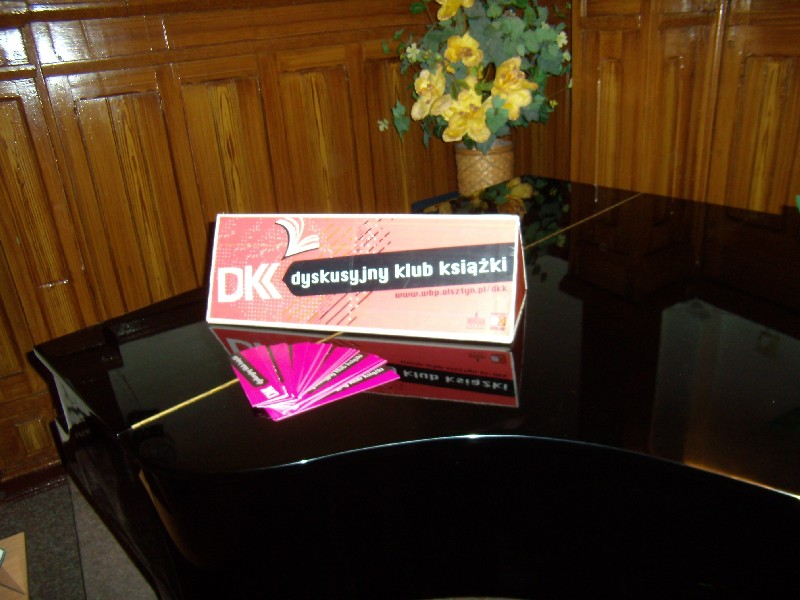 Wnętrze szkoły muzycznej. Czarny fortepian i logo DKK oraz zakładki.