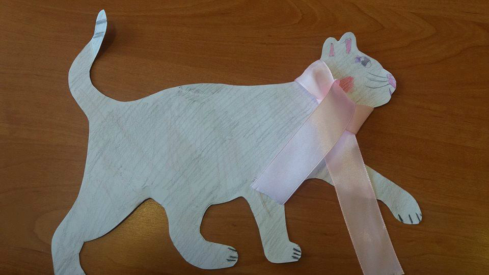 Na stoliku kot wycięty z papieru i przewiązany wstążką.