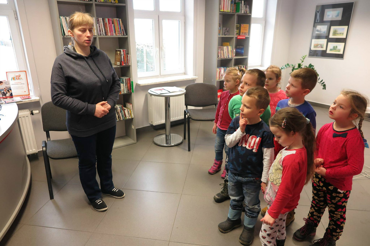 Wnętrze biblioteki,mediateka. bibliotekarka Małgorzata Trąmpczyńska opowiada dzieciom o dziale mediateka.