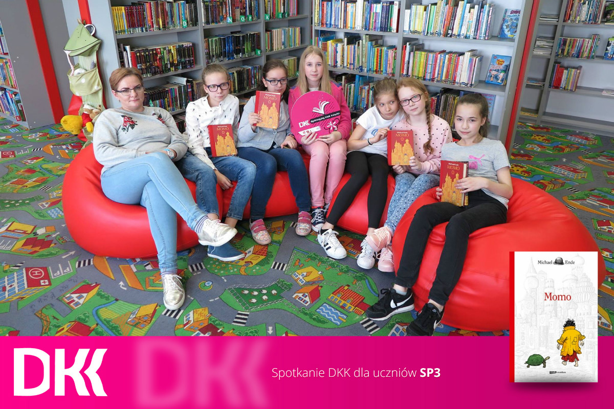 Wnętrze biblioteki. Na czerwonych pufach siedzą uczestnicy klubu DKK SP 3, wspólnie omawiają książkę Michaela Endego "Momo". 