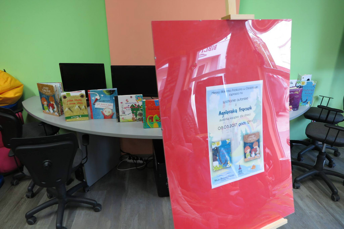 Sztaluga czerwone tło i plakat MBP zaprasza na spotkanie autorskie z Agnieszką Frączek, autorką książek dla dzieci. 