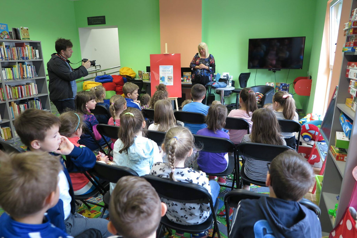 Na krzesełkach siedzą dzieci biorą udział w zajęciach z autorką książek dla dzieci Agnieszką Frączek. 