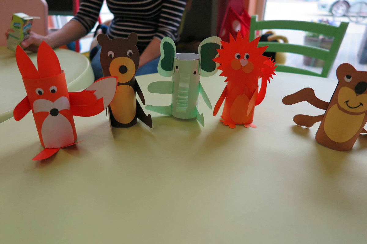 Na stoliku  stoją zwierzątka wykonane przez dzieci z kolorowego papieru. 