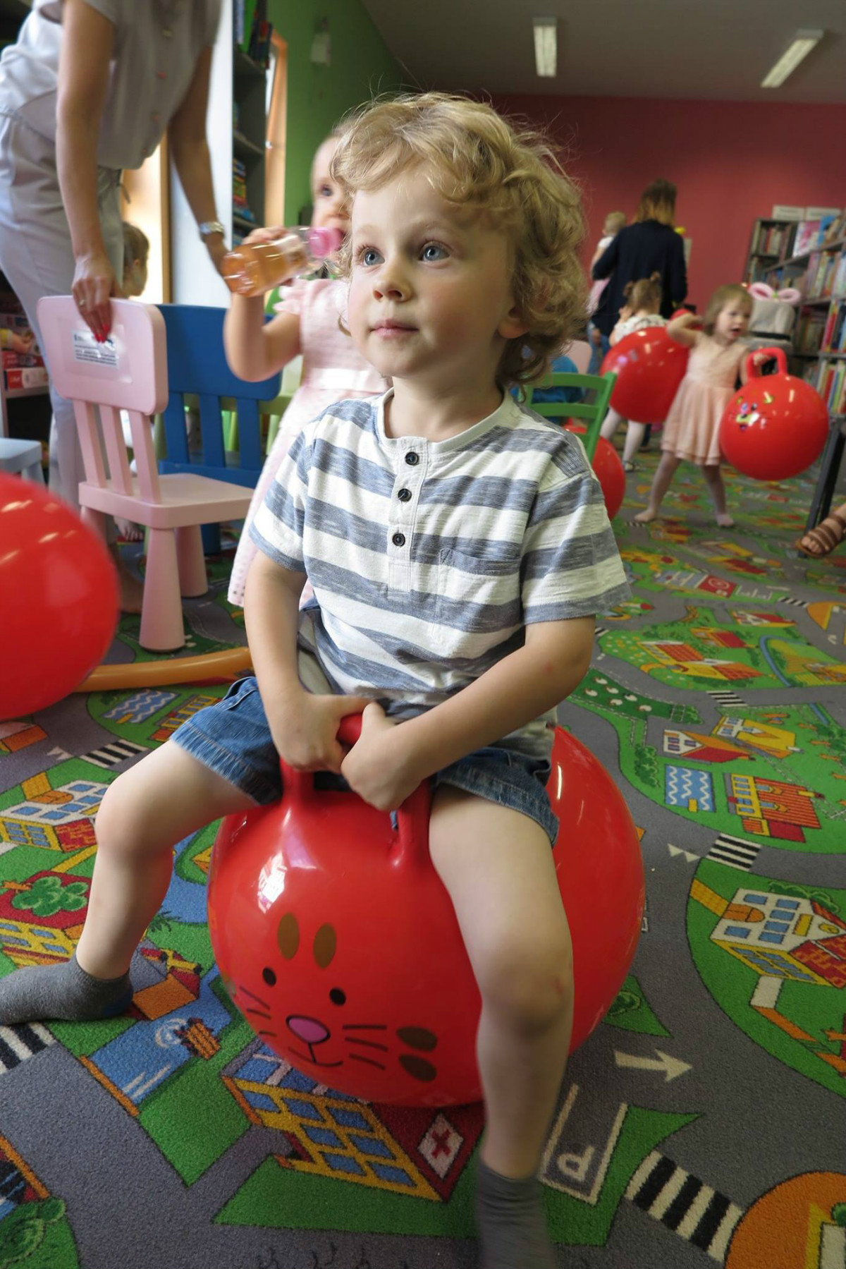 Chłopiec siedzi na czerwonej piłce podczas zakończenia roku w klubie malucha. 