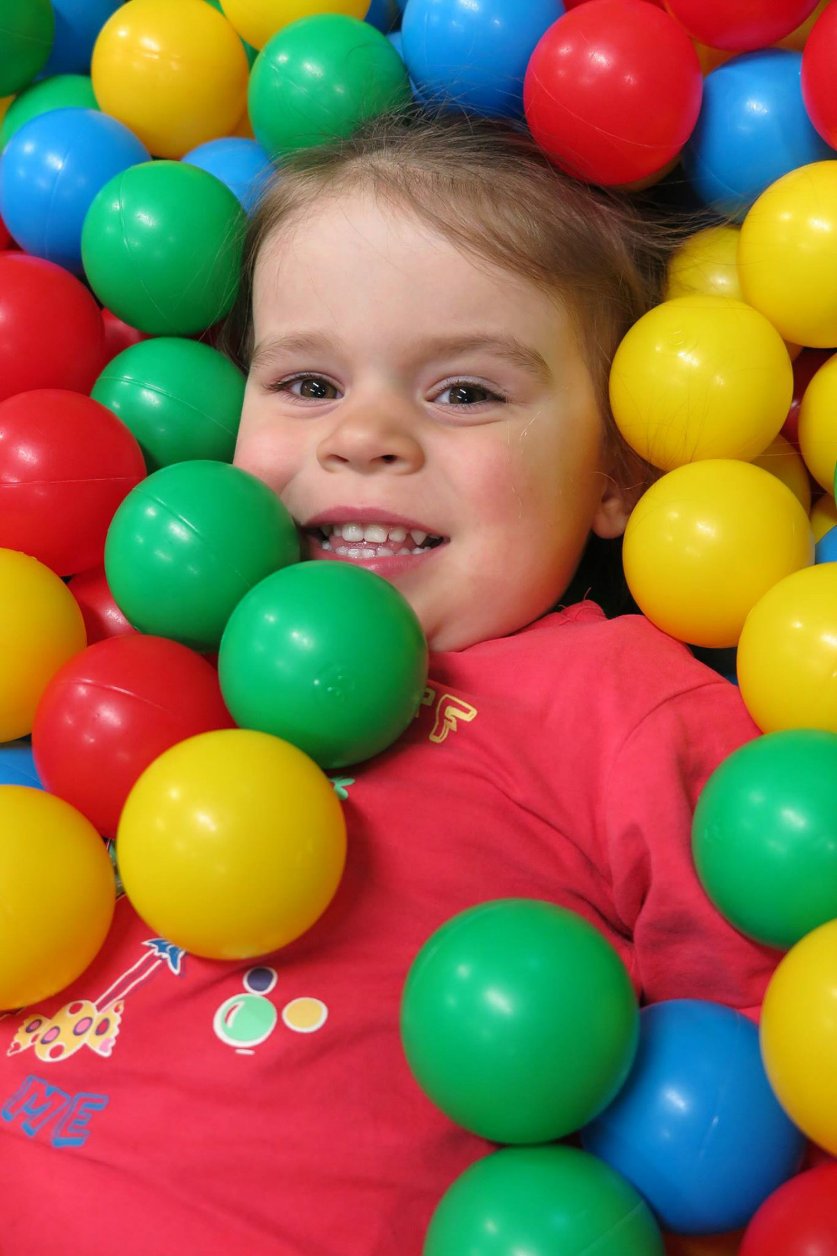 Dziewczynka w basenie z kolorowymi piłeczkami. 