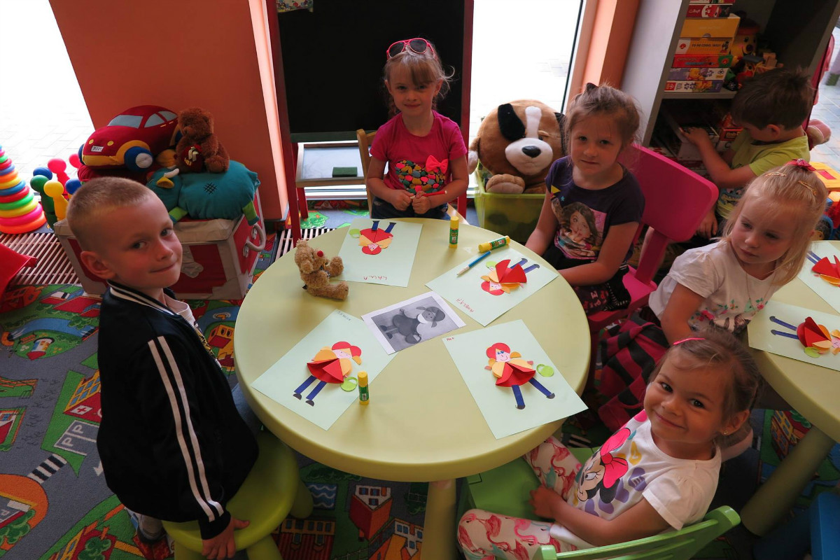 Przy stoliku siedzą dzieci razem wykonują czerwone kapturki.