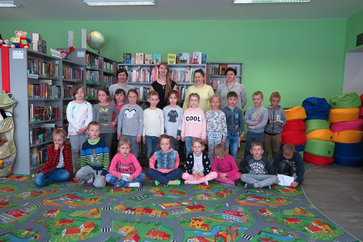 Wnętrze biblioteki. Grupa dzieci z Przedszkola w Narzymiu po lekcji bibliotecznej z bibliotekarkami Aleksandrą Cybulską i Anią Wiśniewską. 