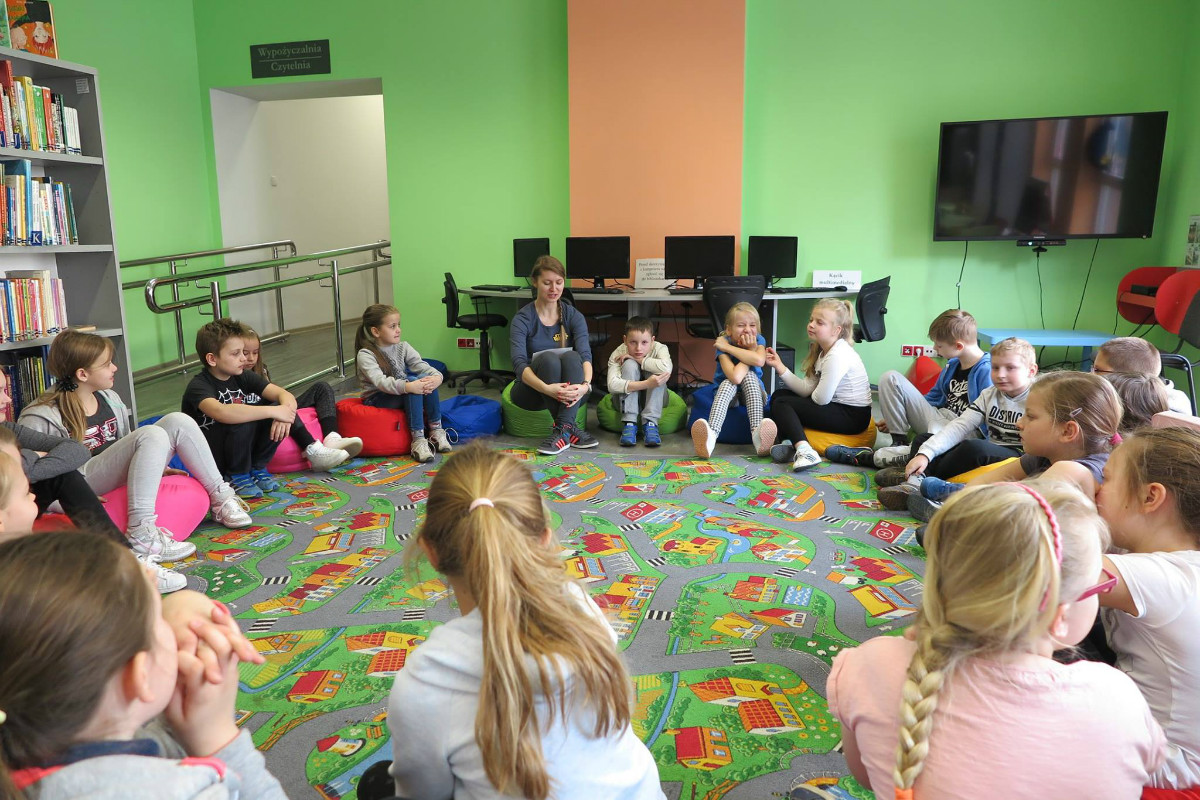 W kole siedzą dzieci, bibliotekarka Ola Cybulska prowadzi zajęcia na temat wartości.