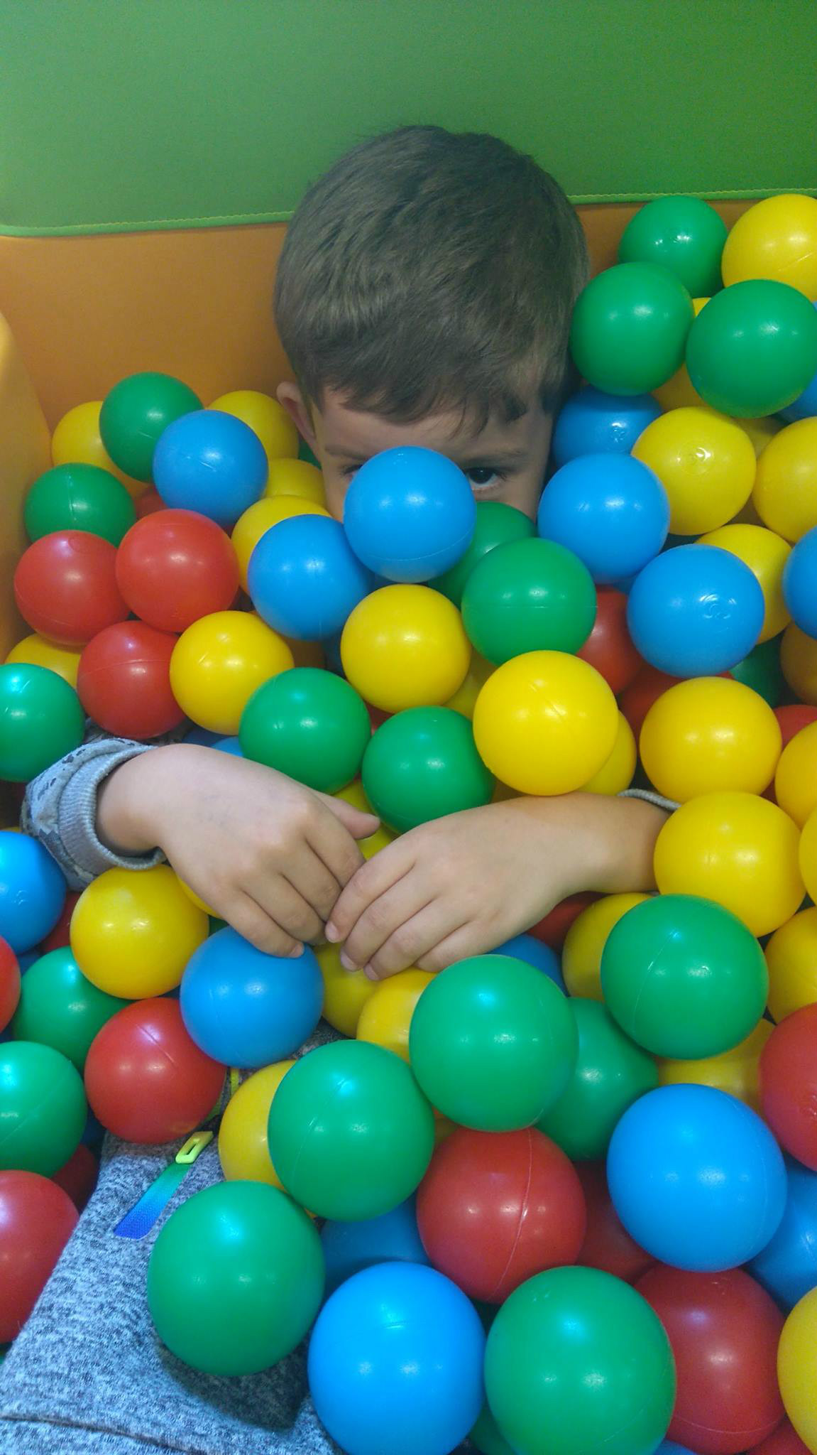 W basenie z kolorowymi piłeczkami bawi się chłopczyk.