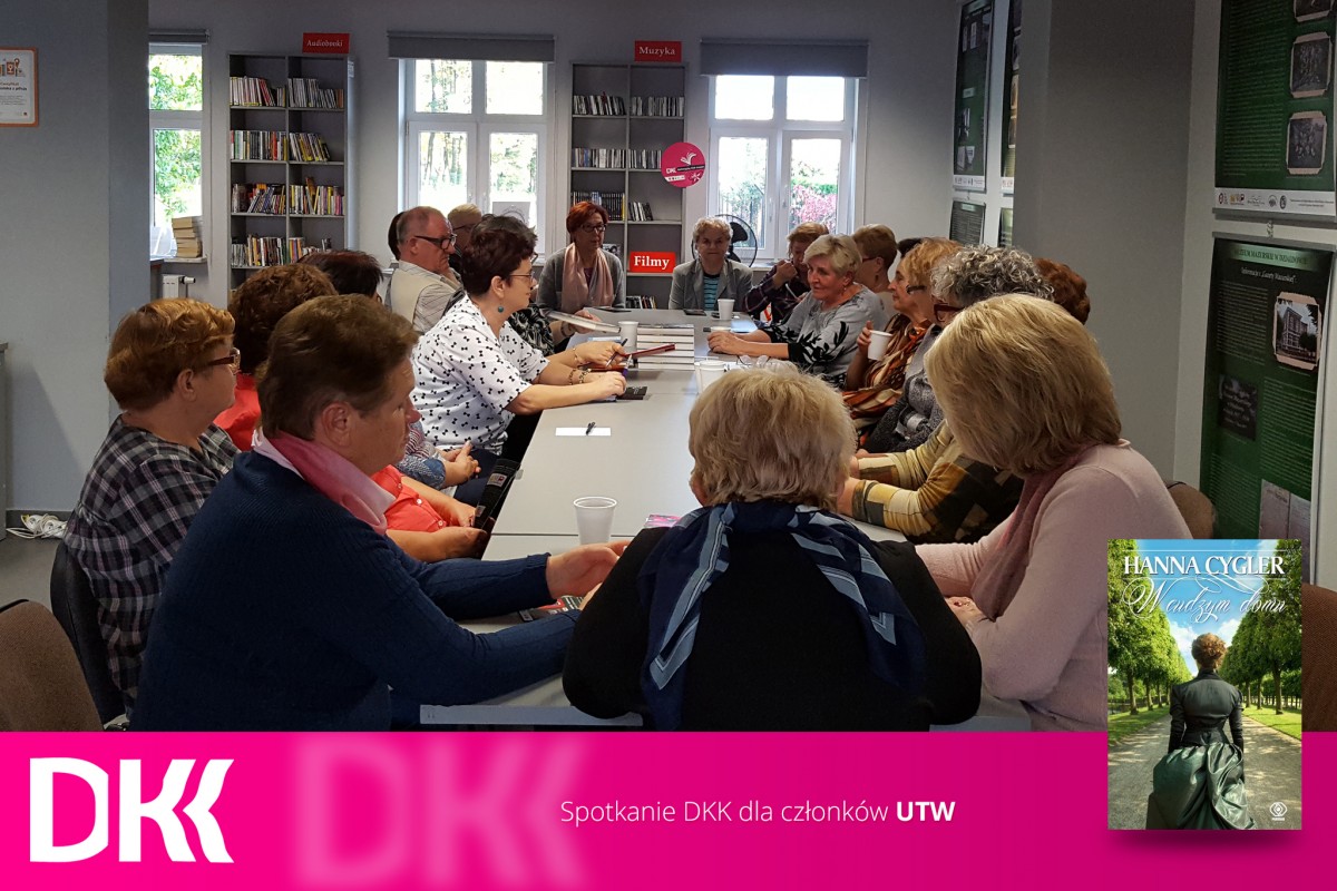 Wnętrze biblioteki,mediateka. Przy stolikach siedzą uczestnicy DKK UTW i dyskutują o książce Hanny Cygler: "W cudzym domu".