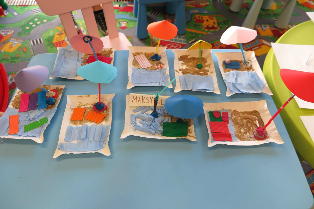 Na stoliku znajduje się 8 wakacyjnych  prac plastycznych dzieci.