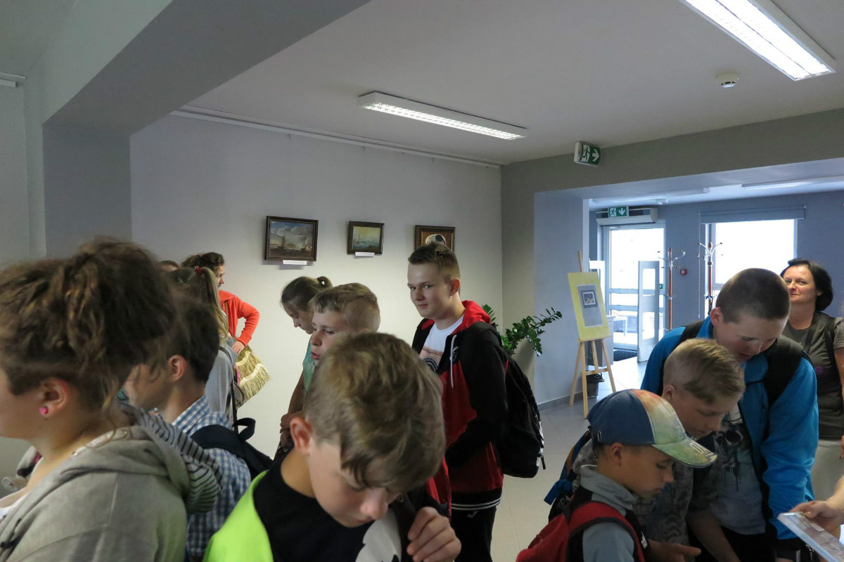 Wnętrze biblioteki. Grupa uczniów ze SP w Petrykozach zwiedza oddział mediateka.