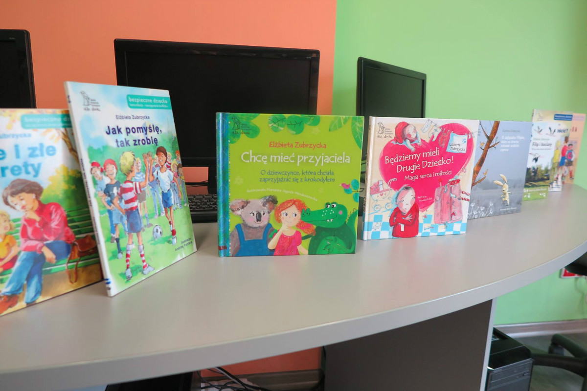 Na stoliku stoją książki dla dzieci autorki Elżbiety Zubrzyckiej. 