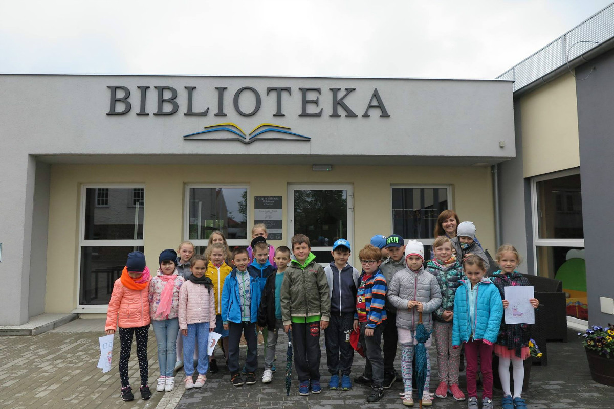 Na placu przed MBP w Działdowie stoi grupa dzieci ze SP nr 4.
