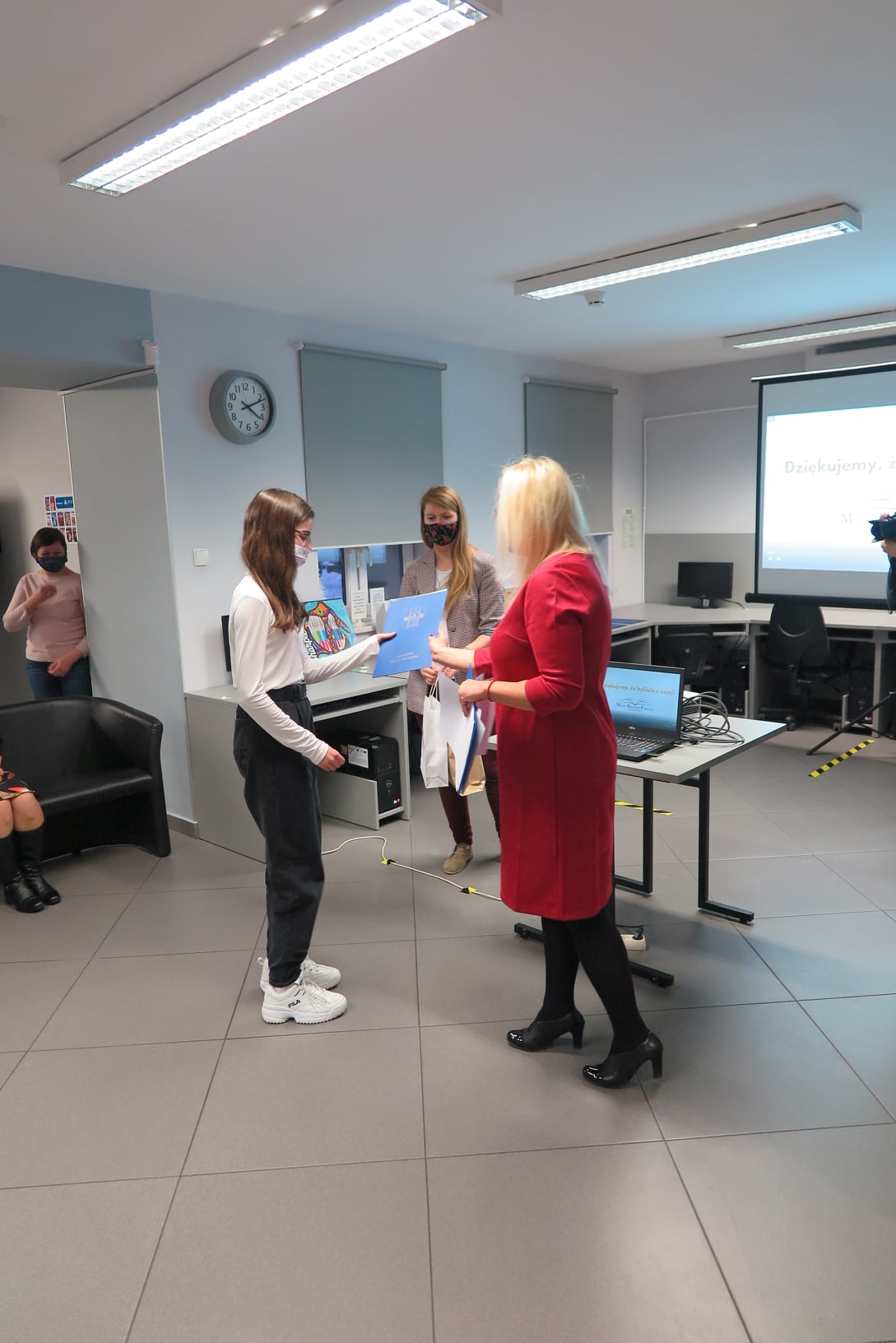 Wnętrze biblioteki mediateka, dyrektor biblioteki Justyna Lytvyn wraz z bibliotekarką Olą Cybulską wręcza nagrodę laureatce. 
