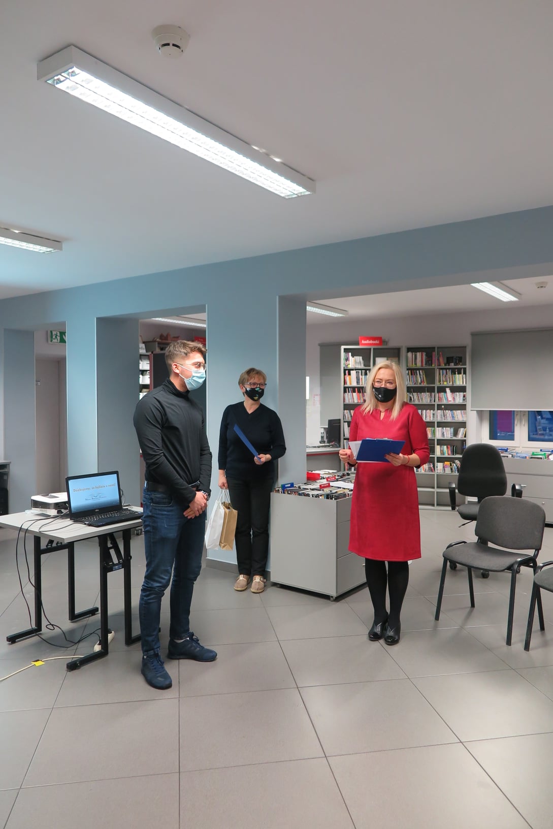 Wnętrze biblioteki mediateka. Dyrektor biblioteki Justyna Lytvyn wraz z kustoszem Elżbietą Wojcieszak wręcza nagrodę laureatowi. 