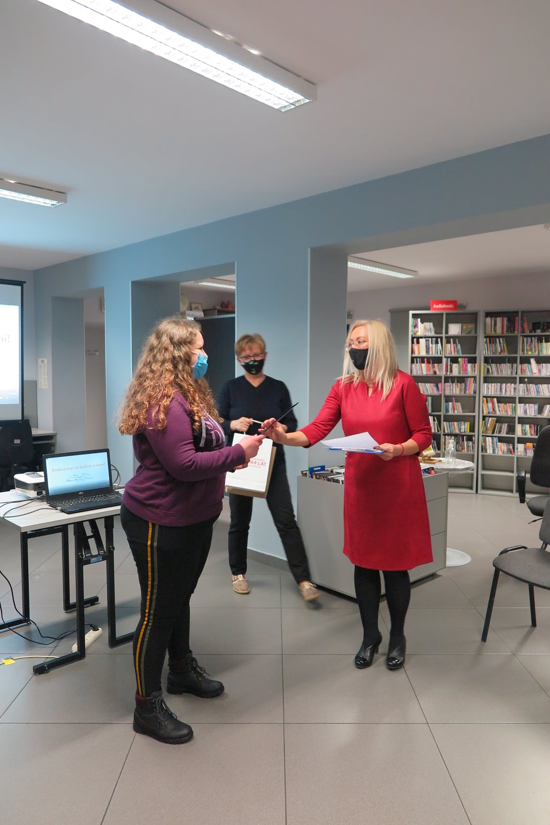 Wnętrze biblioteki mediateka, dyrektor biblioteki Justyna Lytvyn wraz z kustoszem Elżbietą Wojcieszek wręcza nagrodę laureatce. 