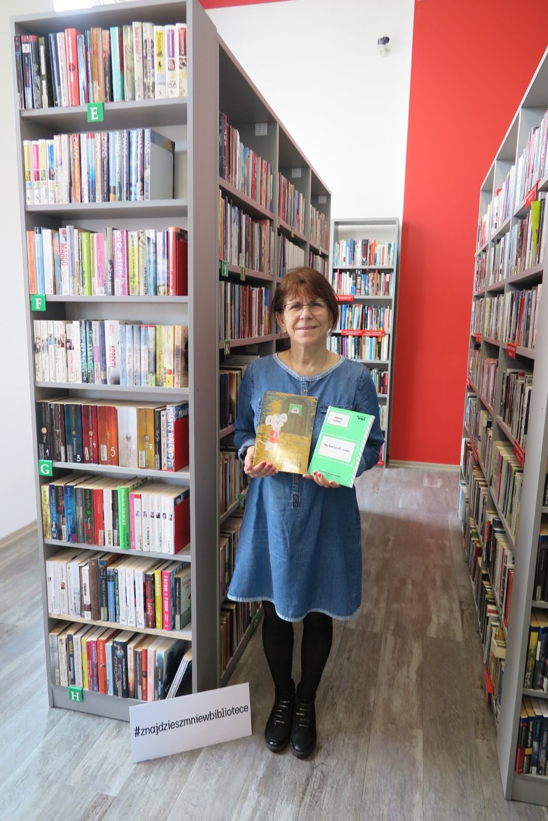 Janina Dzenis pośród książek w bibliotece