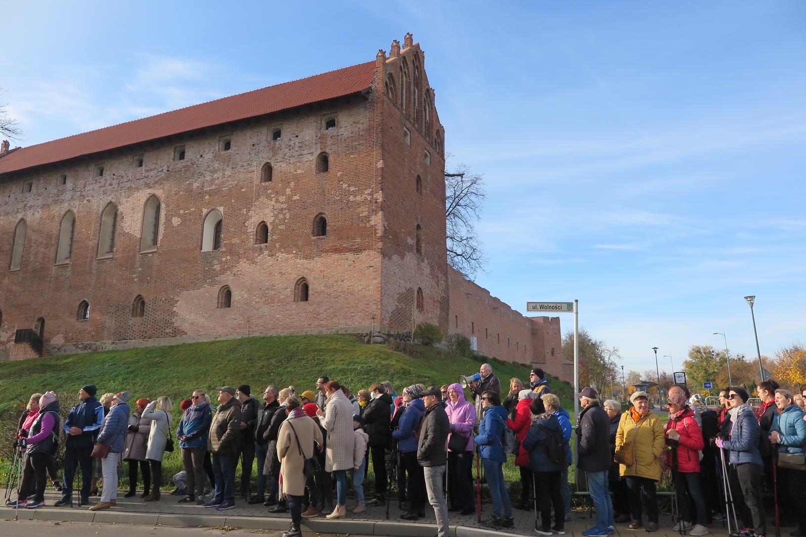 uczestnicy marszu na tle zamku krzyżackiego w działdowie