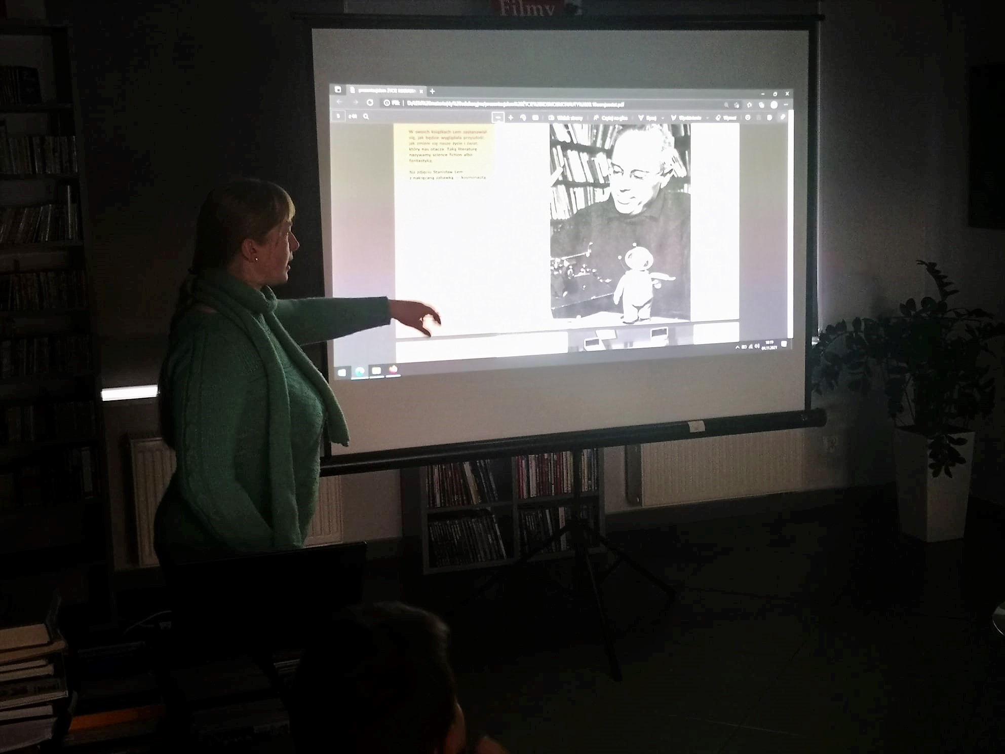 bibliotekarka stoi przy ekranie projektora w ciemnej sali, na ekranie Stanisław Lem