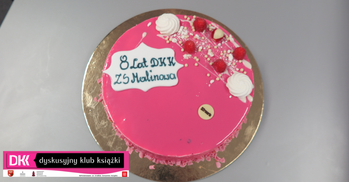 różowy tort z napisem 8 lat DKK ZS Malinowo, leży na stole, w dolnym rogu logo DKK