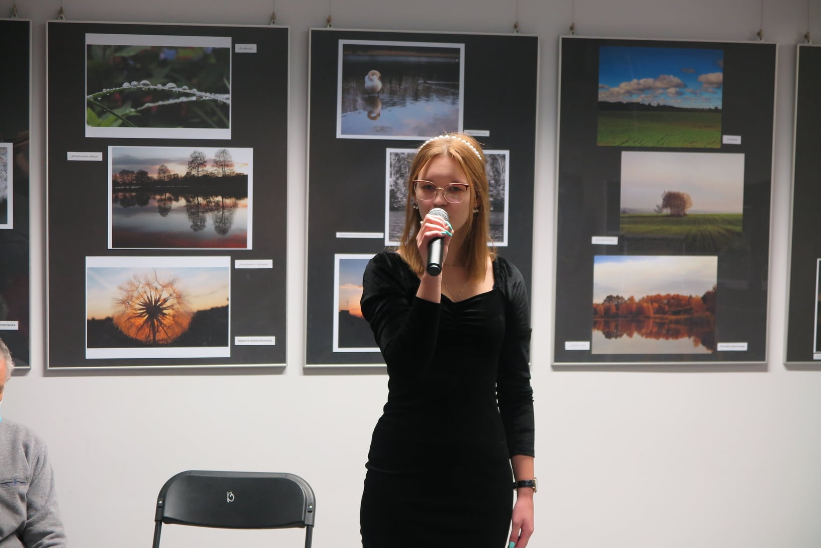 wokalistka  zapewniająca oprawę muzyczną na tle ściany z wystawa fotografii 