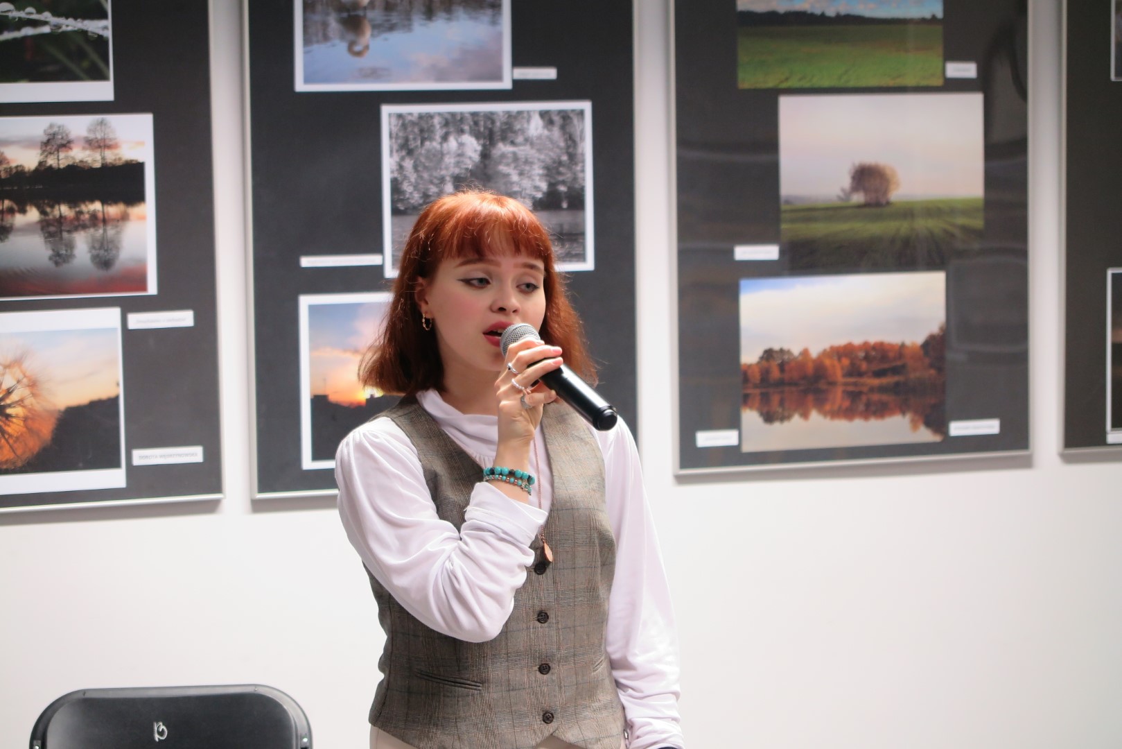 wokalistka  zapewniająca oprawę muzyczną na tle ściany z wystawa fotografii 