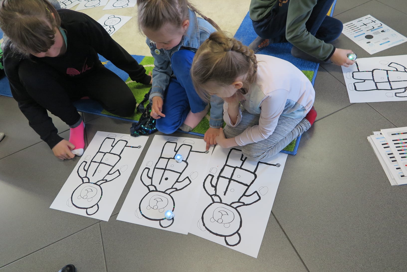 4 dzieci puszcza zoobota po trasie narysowanej w kształcie misia na kartce