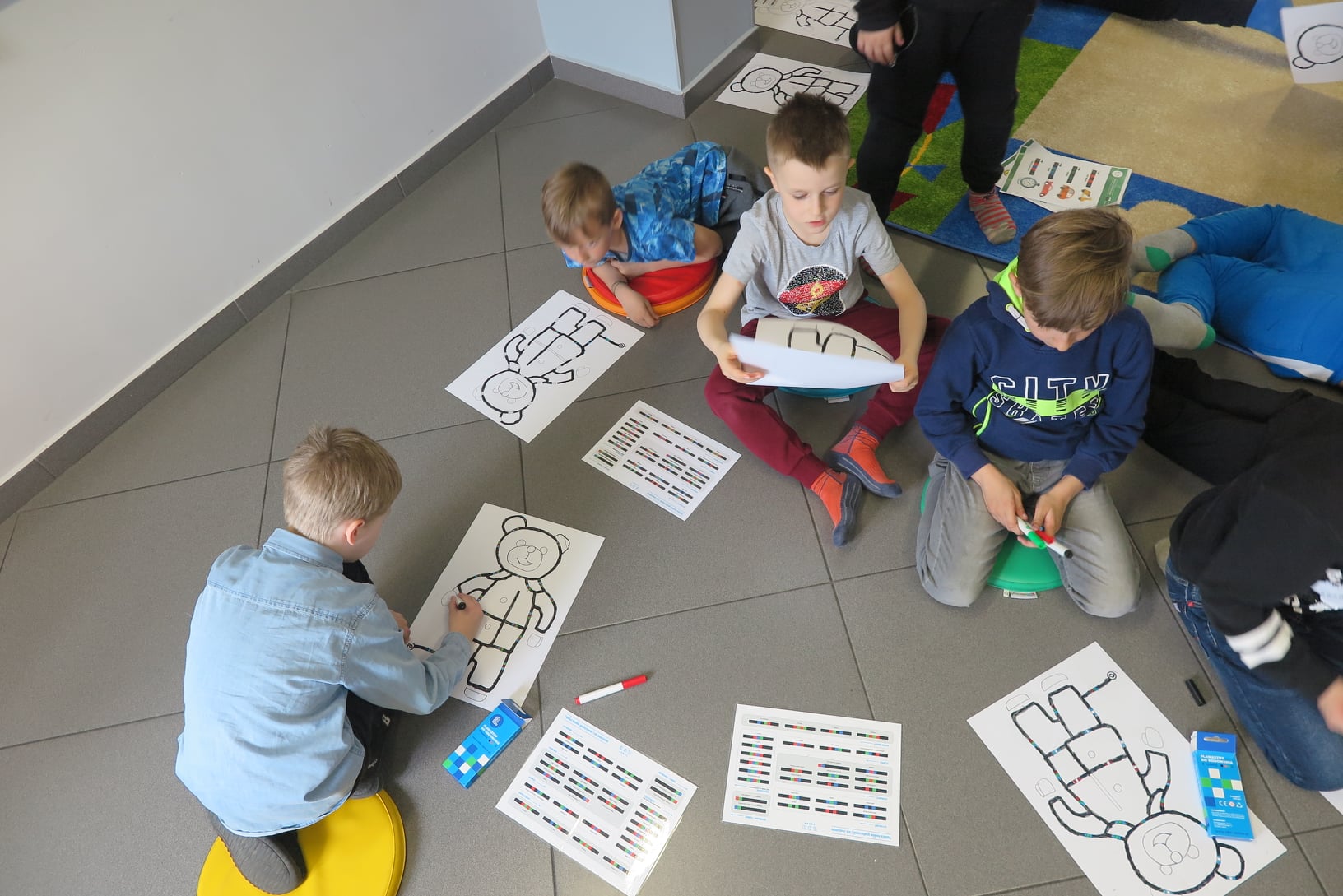 5 dzieci rysuje flamastrami na kartce trasę dla ozobota używając kolorowych kodów