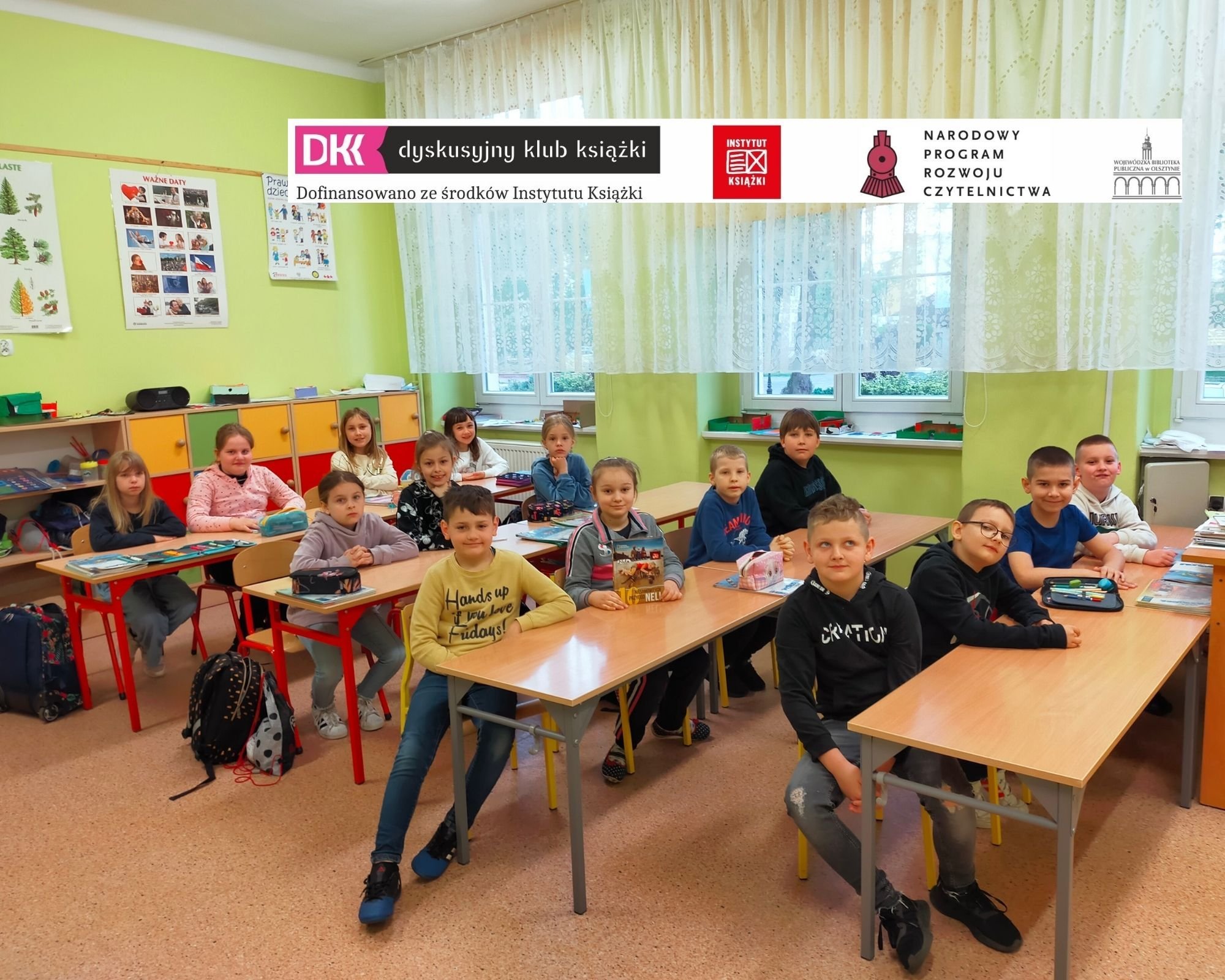 uczniowie, członkowie klubu DKK siedzą w ławkach szkolnych w klasie lekcyjnej