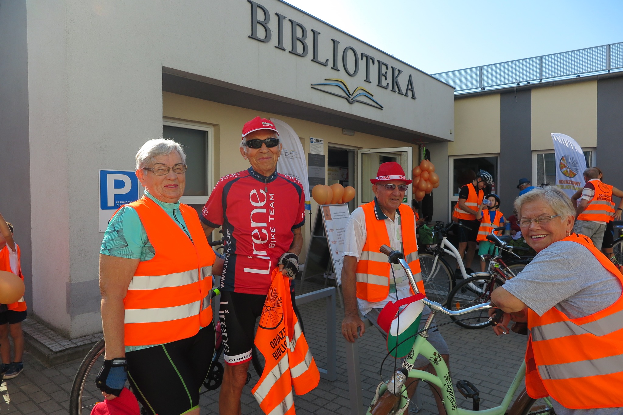 uczestnicy rajdu rowerowego zbierają się przed bibliteką