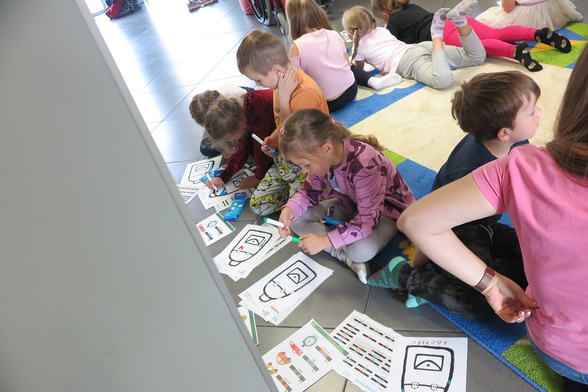 dzieci rysują trasę dla ozobota siedząc na dywanie w mediatece