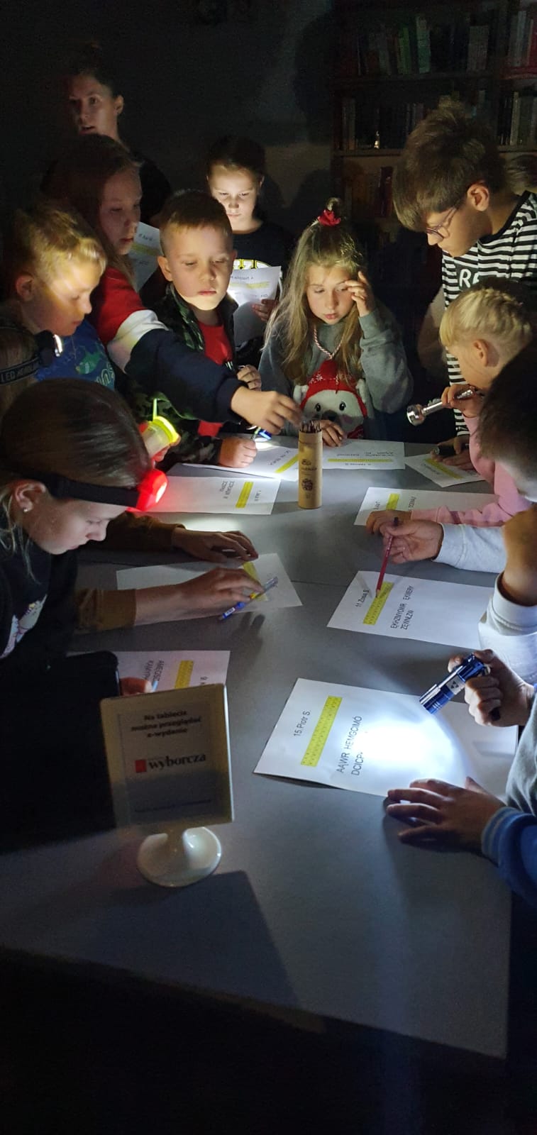 dzieci rozwiązują przy latarkach zagadkę zaginionego misia Szymona 