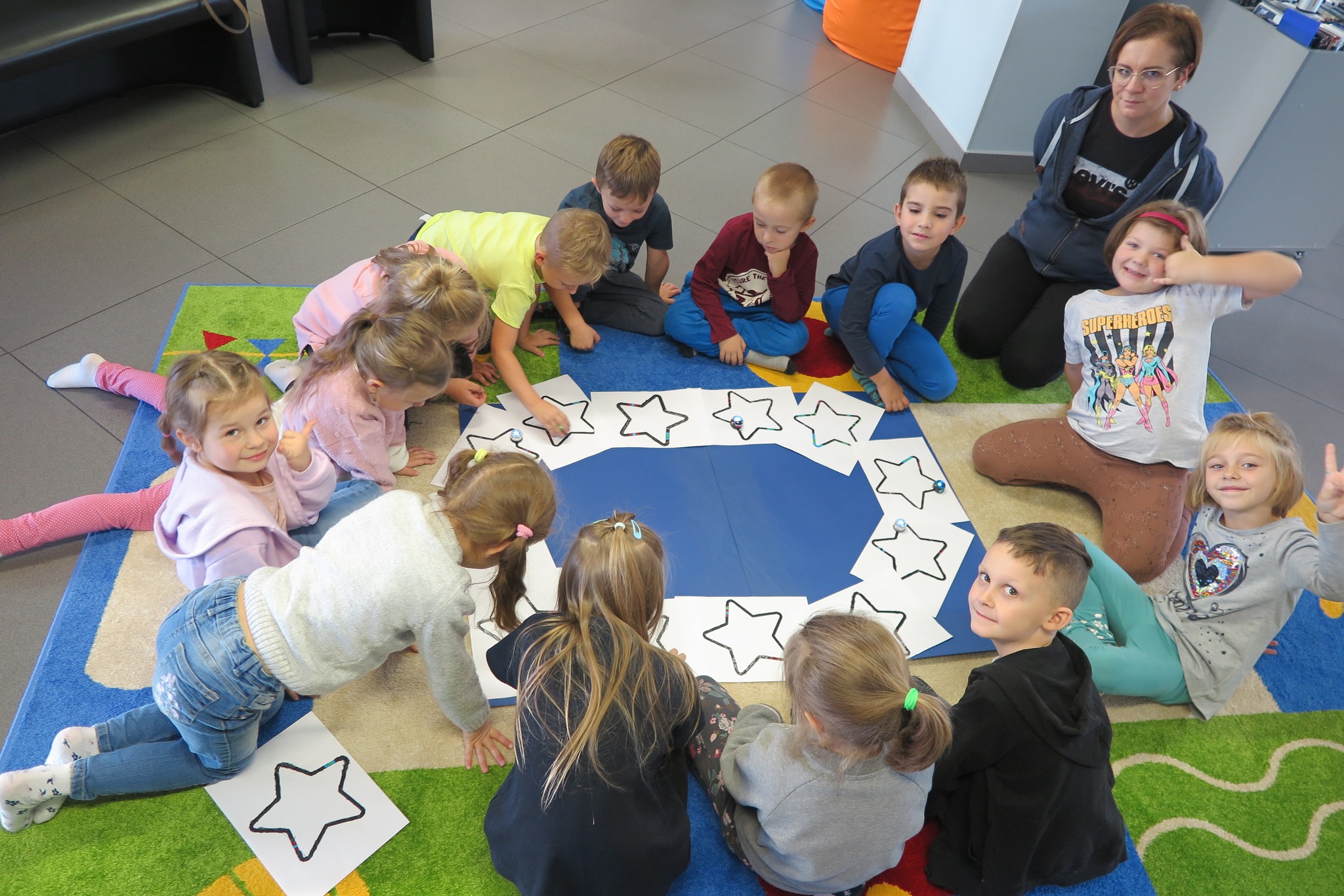 dzieci puszczają ozoboty po gwiazdach narysowanych na kartkach w kształcicie flagi eu