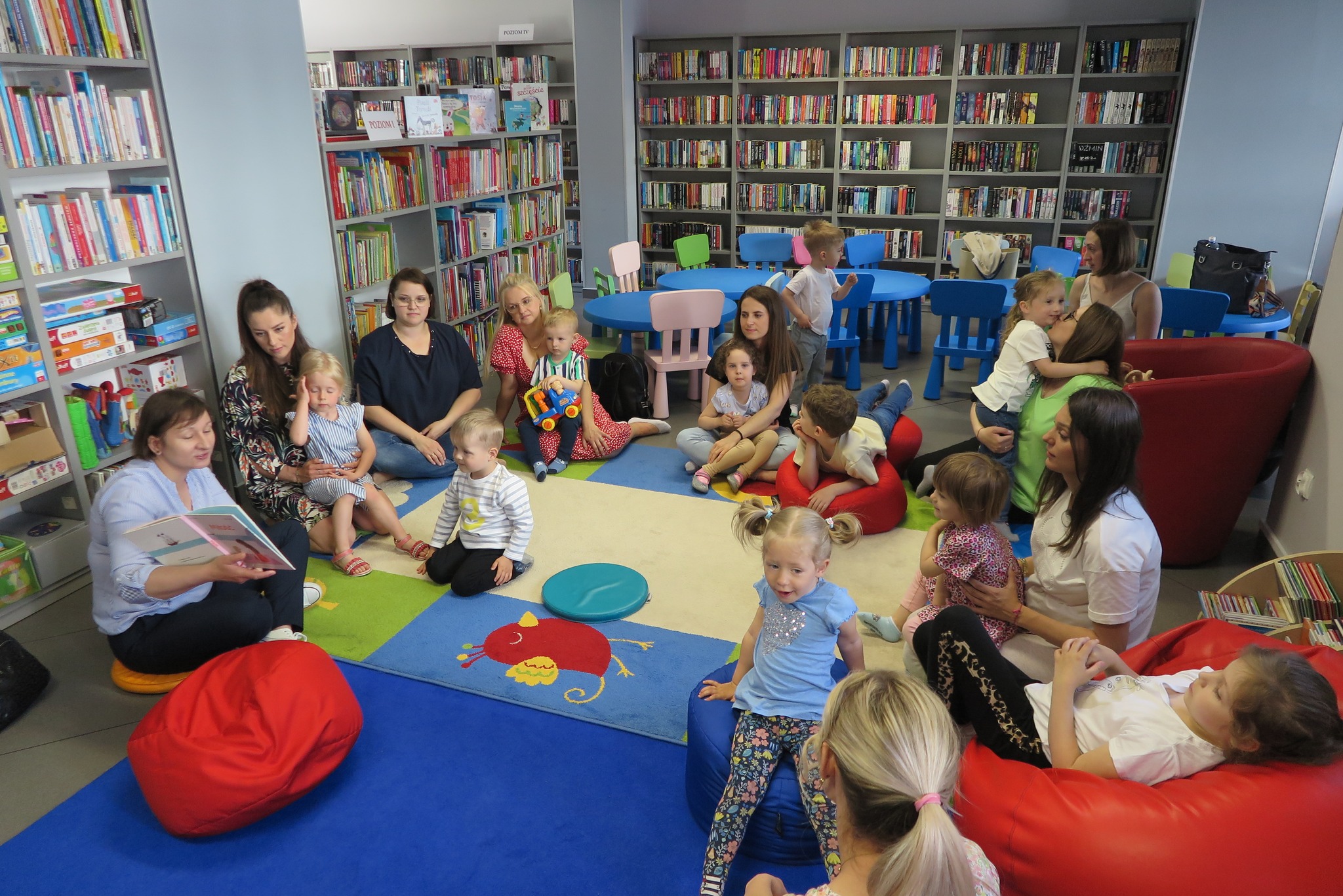dzieci z opiekunami podczas Klubu Malucha słuchają czytanej książki