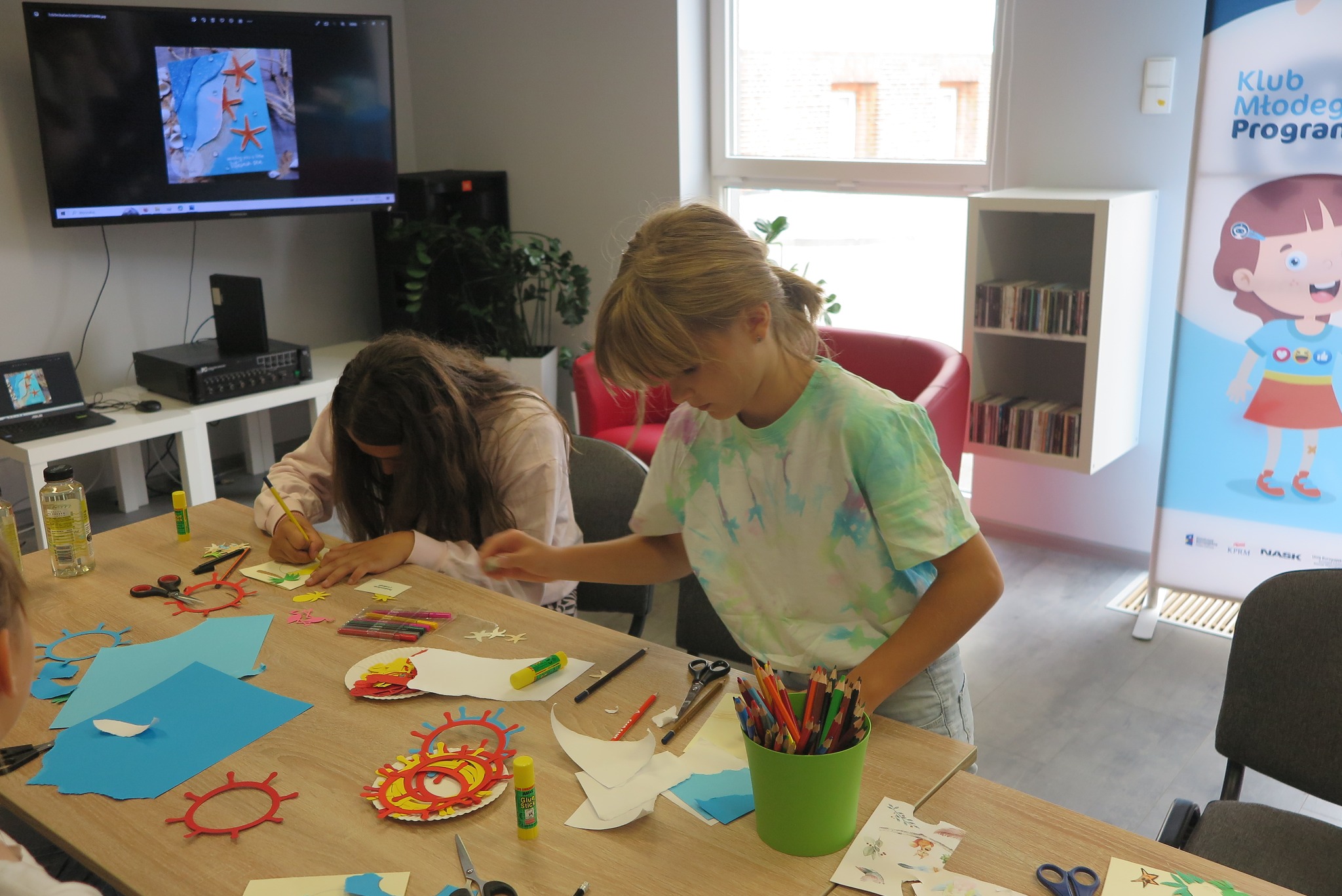 uczestnicy warsztatów plastycznych z tworzenia pocztówek z wakacji podczas zajęć