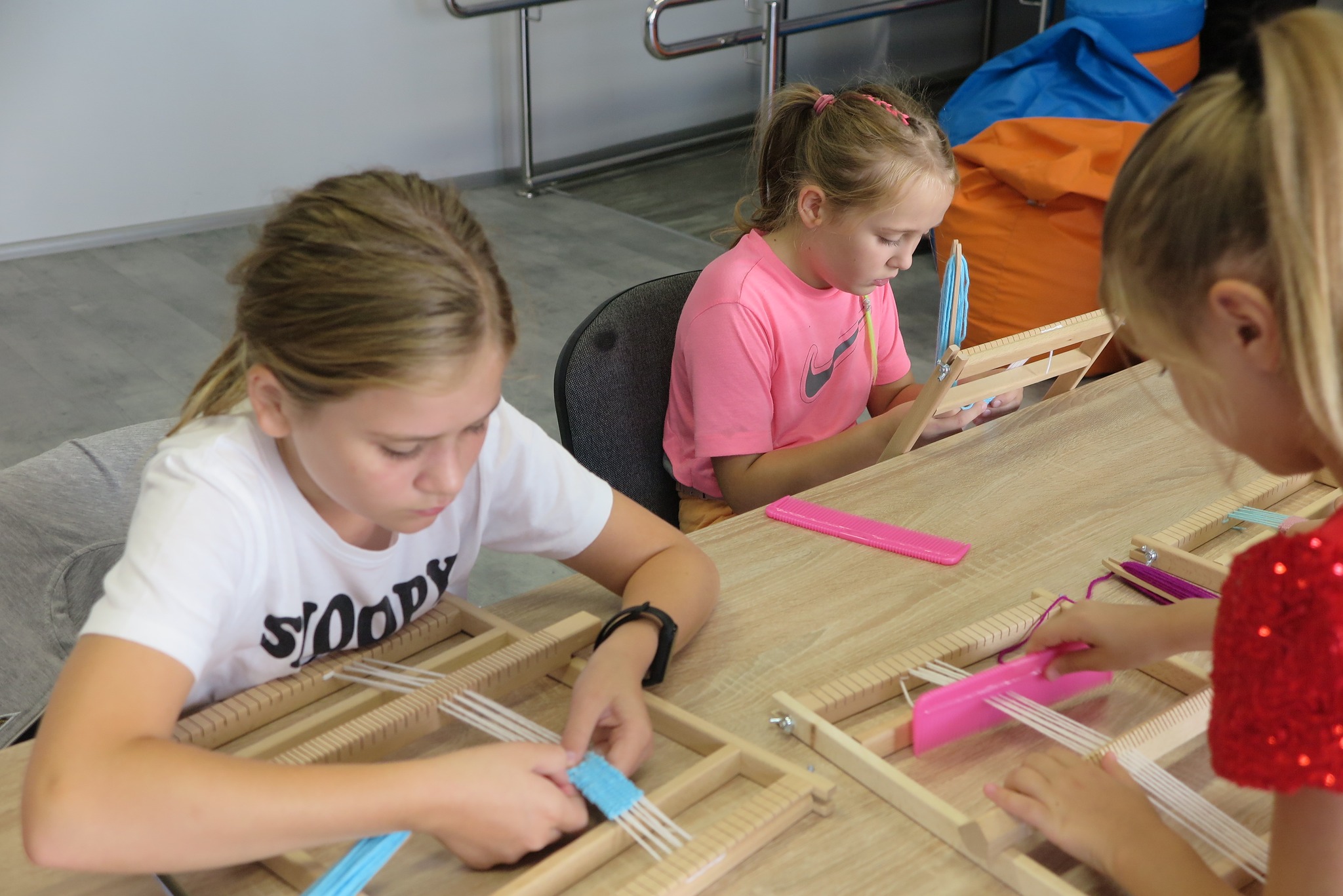 uczestnicy warsztatów tkackich podczas zajęć uczą się tkać na krosnach zakładki do książek