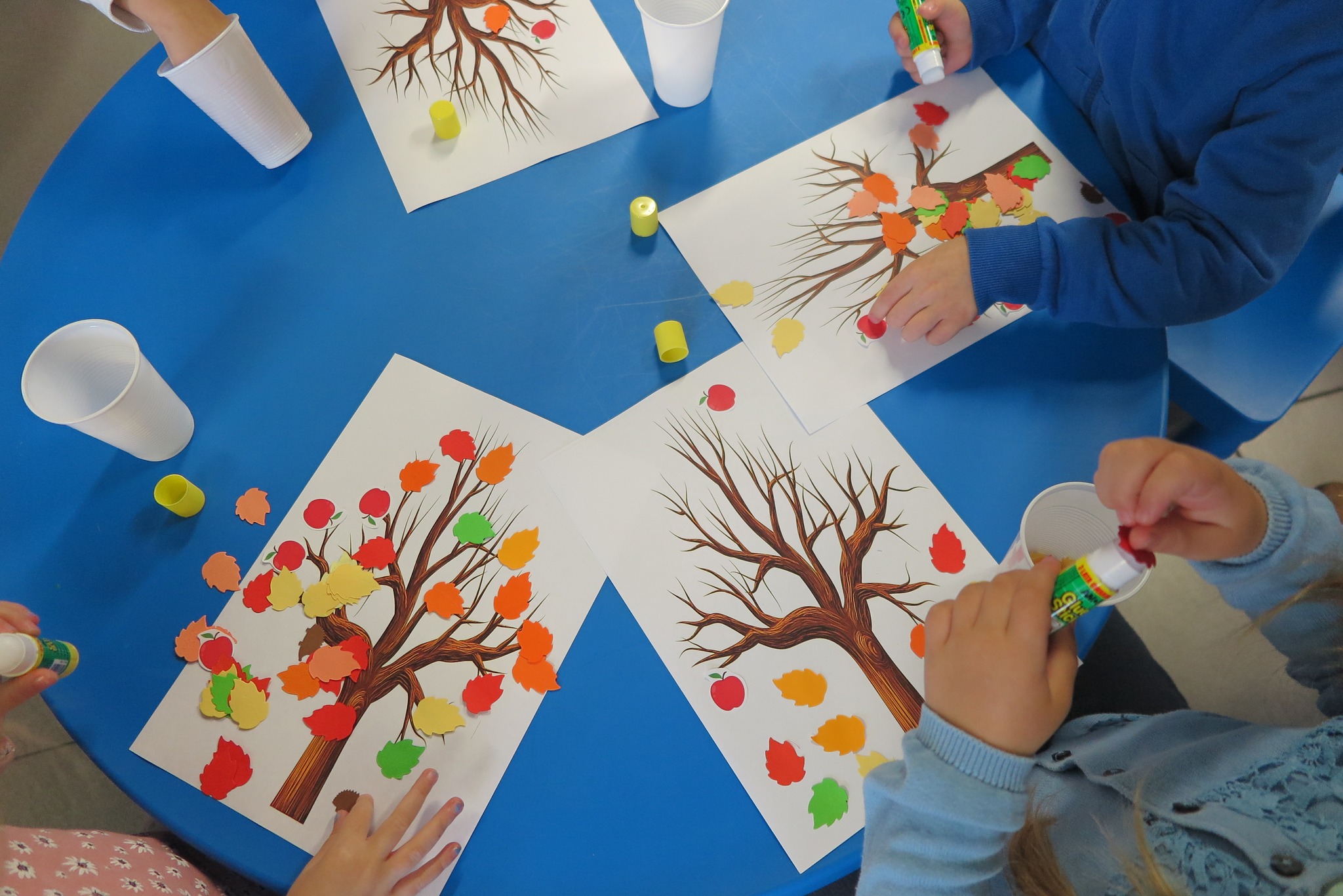 wyklejanie drzewa wydrukowanego na kartce kolorowymi liśćmi z papieru