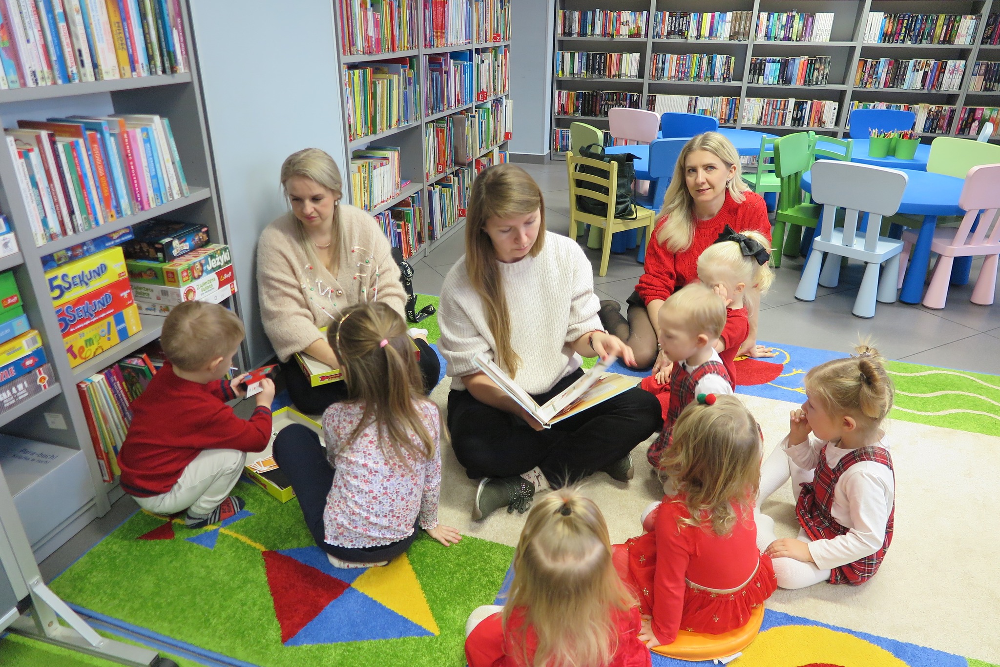 dzieci słuchają czytanej przez bibliotekarkę książki